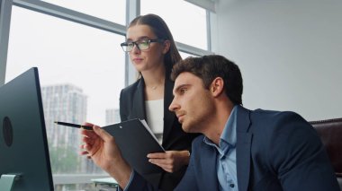 İki yönetici dijital pazarlama raporunu tartışıyor. Odaklanmış asistan şirket stratejisini not alıyor. Başarılı düşünceli yönetici meslektaşına talimat projesi veriyor. Takım birlikte çalışsın.