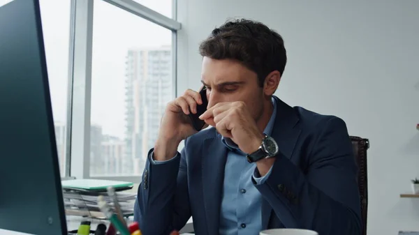 Serious manager speaking mobile phone at workplace. Worried sales man talking dealing customer complaint. Handsome businessman investor speaking with colleague partner. Corporate employee concept.
