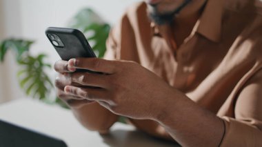 Yakın plan cep telefonu düz arkaplanda erkeklerin elinde. Kahverengi tenli adam açık dairelerde akıllı telefonlara mesaj atıyor. Tanımlanamayan Afrikalı Amerikalı öğrenci hücre sosyal medya okuyor.