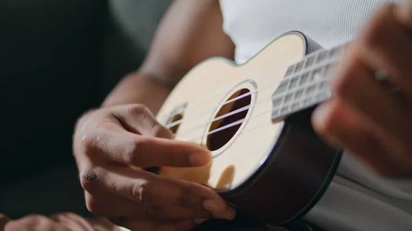内部でウクレレを演奏する男の手 文字列に触れる未知のアフリカ系アメリカ人ミュージシャン 匿名の男は自宅で音楽を楽しんで座っている 茶色の肌のギタリストの腕だけで音を抽出 趣味の概念 — ストック写真