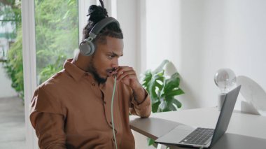 Kulaklıklılar yakın çekimde internetten konuşuyor. Pozitif adam sanal konferansı dizüstü bilgisayarla yapıyor. Eğitimli Afrikalı Amerikan öğretmeni uzaktan iletişim kuruyor.