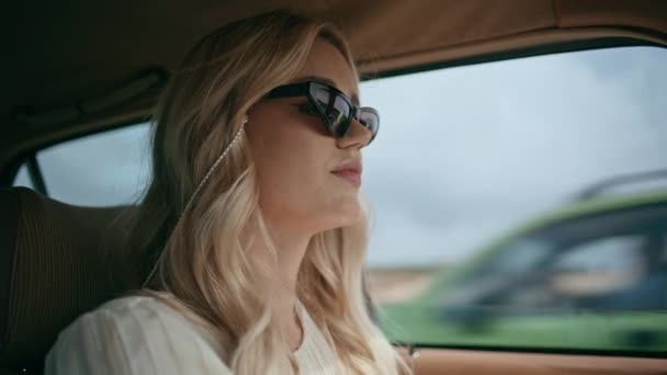 閉じる自信のある女性ドライバー道路曇りの天気に乗る スタイリッシュな若い女性は グラマラスサングラスを身に着けているステアリングホイール古典的な車を運転 若いです屈託のない女の子旅行を使用して自動車 — ストック動画