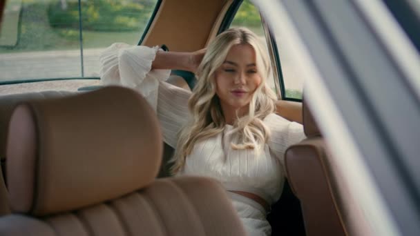 女性は近くの後部座席高級サロンに座ってレトロな車をお楽しみください ヴィンテージ自動車の中にドアにもたれてポーズ美しいモデル 自動車でリラックスした魅惑的なブロンドの女の子を自信を持って 車両旅行 — ストック動画