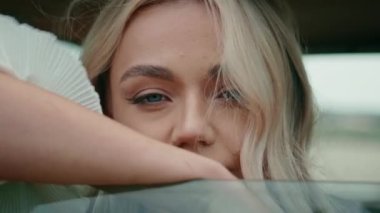 Otomobil vitrininde güzel bir kadının portresi. Çekici genç sarışın yüz kameraya güvenli bir şekilde yaklaşıyor. Muhteşem rahat kız arka koltukta oturmuş açık pencereden bakıyor..