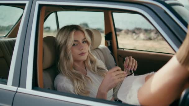 漂亮的女乘客坐在复古汽车里放松一下 把漂亮的腿放在开着的窗户旁边 迷人的女孩 戴着太阳镜 坐在舒适的老式汽车上 旅行旅行概念 — 图库视频影像