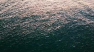 Kapalı deniz dalgalanması sabah güneşini yansıtıyor. Drone görüntüsü sakin mavi yaz gölü süper yavaş çekim. Turkuaz su gündüz vakti dolanıyor. Sakin dalgalar yavaşça hareket ediyor. Deniz doğası kavramı