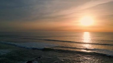Güneşin doğuşu dalgalı deniz sahili hava manzarası. Karanlık ve dingin okyanus yüzeyinde altın şafak. Gün batımında ağır çekimde hareket eden huzurlu dalgalar. Meditasyon yapan sakin deniz manzarası 