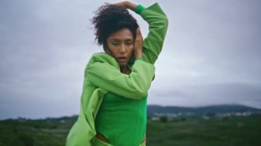 Afrika kökenli Amerikalı kadın sanatçı gri bulutlu gökyüzünde anlamlı modern koreografi dansı yapıyor. Şehvetli dansçı kız esnek vücudu karanlık bir akşamda dışarıda duruyor. Yetenek konsepti.