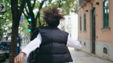 Yürüyen şehir caddesinde dans eden aktif mutlu kadın. Yaklaş. Neşeli Afro-Amerikalı kız gülümseyerek kameraya doğru zıplıyor. Açık havada serbest dans eden genç bir bayan dansçı. Dans konsepti.