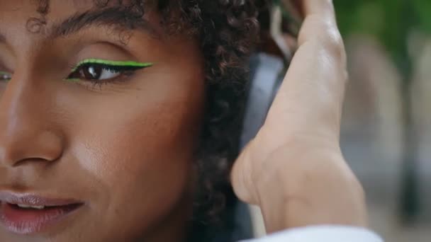 밀폐된 밖에서 헤드폰을 카메라를 매력적 아프리카 미국인 여자가 곱슬곱슬 스타일의 — 비디오
