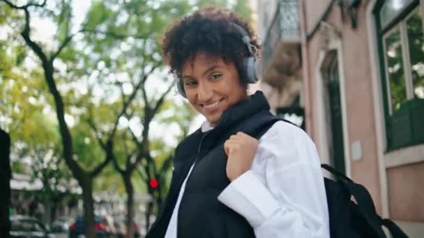 Θετικό Κορίτσι Τουριστικό Δρόμο Περπάτημα Φορώντας Σύγχρονα Ακουστικά Κοντά Χαρούμενη — Αρχείο Βίντεο