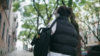 Neşeli funky kadın dans ederken kablosuz kulaklıklarla dışarıda müzik dinliyor. Mutlu Afrikalı Amerikalı kız modern kulaklıklarda sesin tadını çıkartıyor. Gülümseyen bayan turist sokakta geziniyor.