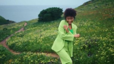 Neşeli, mutlu bir kadın çiçek bahçesinde aktif dans ediyor. Gülümseyen Afrikalı Amerikalı kız akşam doğasında serbest dans ediyor. Kıvırcık kadın ağır çekimde modern koreografi uyguluyor.