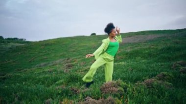 Boş yeşil bir sonbahar akşamında çağdaş dans eden şehvetli kadın sanatçı. Parlak Afrikalı Amerikalı dansçı kız doğada düzgün vücut hareketleri yapıyor. Kendine güveni tam bir bayan..