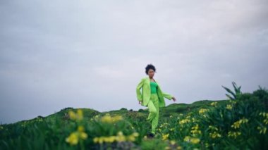 Güzel kır çiçekleriyle dans eden yetenekli genç bir kız. Kıvırcık Afrikalı Amerikalı kadın kasvetli doğada şefkatle dans ediyor. İlham verici dansçı etrafında dönüyor Performansın keyfini çıkar.