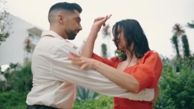 Yeşil şehir parkında tutkulu bir şekilde salsa yapan enerjik dansçılar. İki profesyonel sanatçı dışarıda Latin koreografisi çalışıyor. Baştan çıkarıcı kadın, erkeğin elinde ağır çekimde dönüyor.