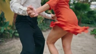 Şehir parkında Latin Amerika tarzı koreografi yapan mutlu sokak dansçıları. Genç profesyonel sanatçılar ağır çekimde enerjik hareketler yapıyor. Dans ederken kalçalarını sallayan gülümseyen kadın..