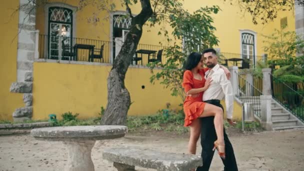 火辣的拉蒂诺舞者在公园的夏日摆出姿势 漂亮的女人穿着红色的衣服靠在男伴身上 一对充满热情的职业情侣站在黄色的城楼前 — 图库视频影像