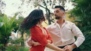 Güzel şehir parkında samba yapan seksi dansçılar. Şehvetli esmer kadın, profesyonel partneriyle tutkuyla hareket ediyor. Seksi çift ağır çekimde Latin koreografisi yapıyor..