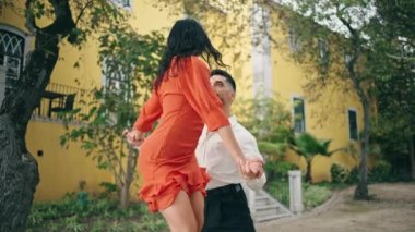 Profesyonel çift, şehir parkında rumba dansı yapıyor. Kırmızı elbiseli seksi bir kadın zarif bir erkekle dans ediyor. Birkaç sanatçı tutkulu bir şekilde Latin tarzını yavaş çekimde açık havada icra ediyor..