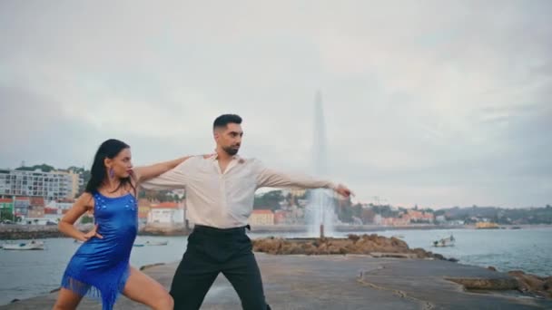 活跃的年轻夫妇在多云的河堤上跳着拉蒂诺舞曲 精力充沛的舞蹈家表演激情舞 动作缓慢 西班牙裔表演者在阴暗的海岸欣赏火爆的舞蹈表演 — 图库视频影像