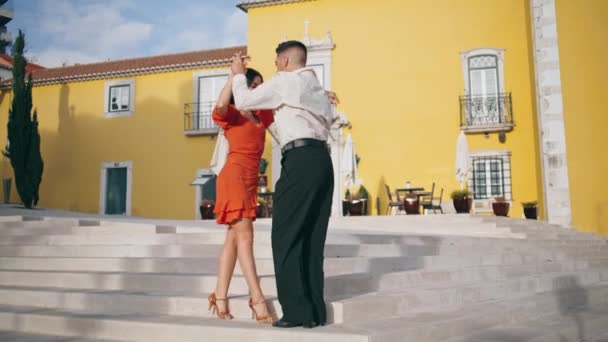 专业的拉丁舞蹈表演者在城市的楼梯上热情地移动 穿着红衣服的漂亮女人和舞伴跳桑巴舞曲 以慢动作表演诱惑力动作的性感伴侣 — 图库视频影像