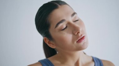 Yogi modeli evde boynu gerdirerek ısınıyor. Sıska sporcu kadın, beyaz duvar dairesinde egzersiz yapıyor. Genç, dingin bir kadın evde tek başına antrenman yapmadan önce başını ısıtıyor.