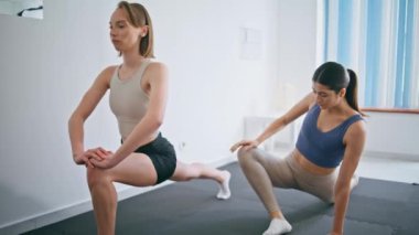 Spor kızları hafif iç mekanlarda çömelme egzersizleri yapıyorlar. Atletik kadınlar vücut geliştirme antrenmanında hamleler yaparak güç gösterisi yapıyorlar. Formda antrenör öğrenci ısınma egzersizlerinin keyfini çıkarın. 