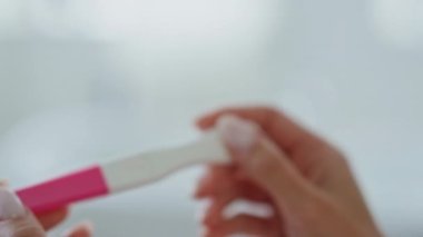 Kız elleri evde hamilelik testi sonuçlarını bekliyor. Banyoda boş plastik test kiti arayan isimsiz bir bayan. Kadın parmakları tıbbi cihazı içeride tek başına tutuyor. Annelik ve annelik kavramı