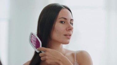 Rahatlamış kız saç modelini yakından çek. Banyoda ipek gibi saçlarını tarayan, ayna yansıması olan huzurlu bir kadın. Gülümseyen, çekici bir kadın, sabahları Chevelure 'yi fırçalıyor. Günlük güzellik rutini