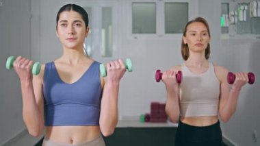 Deniz feneri kapanışında spor yapan iki dambıl. Atletik kadınlar vücut geliştirme antrenmanlarında güç gösterisi yapıyorlar. Ağırlık tutan arkadaşlar birlikte egzersiz yapıyorlar. 