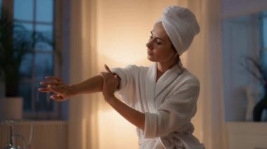 Bakımlı kadın akşam banyosunda kollarını nemlendiriyor. Cilt hastalığının keyfini çıkararak el kremi sürerken yakın plan sakinliği. Tatmin olmuş bir bayan mumların yanına vücut losyonu koyuyor. Eller ilgilenir