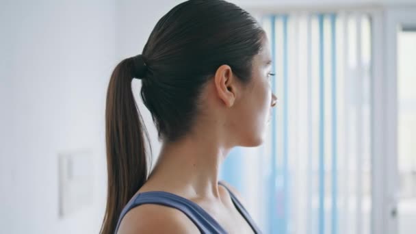 特技队女运动员在窗前练习头部 平静的女孩面对着在白色的家进行颈部训练 吸引人的瑜伽女士温热身体在轻墙公寓锻炼 体育概念 — 图库视频影像