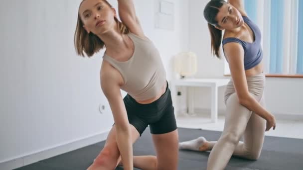 柔韧的女士弯着腰到屋里去了 身材苗条的女运动员单膝伸展腰部肌肉站在轻盈的家 体形匀称的女子训练平衡练习瑜伽 体育常规概念 — 图库视频影像