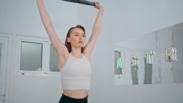 健身模型在家里使用弹性皮带进行武器锻炼 体育女运动员抱着橡皮筋在国内演播室训练 注重运动的女孩喜欢伸展运动 力量和动机 — 图库视频影像
