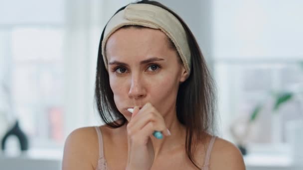 醒来的女人在浴室里刷牙 认真的女士拿着牙刷 在早上的特写镜头里做深度漱口水 居家肖像画中 长发模特独自照顾牙齿健康 — 图库视频影像