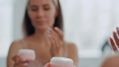 Banyo kapanışında tatmin olmuş, nemlendirici bir yüz. Tımarcı kadın elinde pembe kavanozla yüz temeline başvuruyor. Rahat bir kadın sabah kendi başının çaresine bakıyor. Profesyonel bakım ürünü konsepti