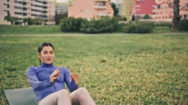 Aktif spor kadın karın egzersizleri parkta yapılıyor. Bulutlu bir günde el ele tutuşan iki spor partneri. Güçlü motivasyonlu kızlar yeşil çim arazisinde vücut geliştirme egzersizinden zevk alıyorlar.