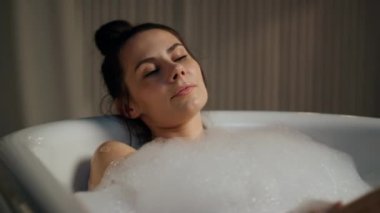 Şehvetli manken akşam tuvaletinde spa rutininin tadını çıkarıyor. Sakin bir kadın evinde köpük banyosuna dokunuyor. Baloncuklarda serinleyen seksi nazik bayan içeride sıvı halde. Güzellik prosedürleri konsepti