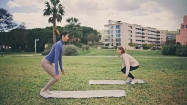Glade 'de burpee egzersizi yapan güçlü sporcular. Genç aktif kızlar birlikte yüksek yoğunluklu antrenman yapıyorlar. Kadınların bahar aylarında kardiyo çekirdeğini güçlendirme egzersizi yapmaları motive edici.