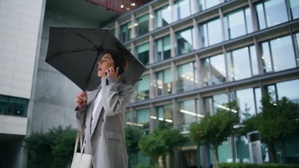 女商人在雨天打电话来 办公室职员在市中心金融中心谈话 自信的女人在现代建筑面试后得到了新的工作机会 中年干部拿着雨伞 — 图库视频影像