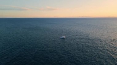 Huzur gününde okyanusta gezen lüks yelkenli. İHA manzaralı beyaz yat, derin gölde tek başına deniz kıyısında yüzüyor. Yüzen özel bir yelkenli, sakin bir su. Seyahat ve turizm konsepti