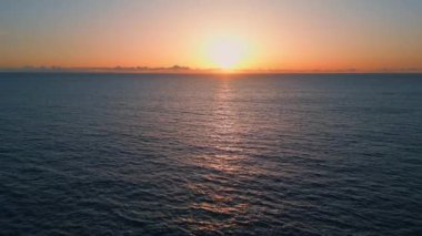 Turuncu günbatımı deniz ufku insansız hava aracı manzarası. Panoramik pembe siluet dalgalanan sakin dalgalar. Gün batımının sakin ve sulu sulara yansıması. Sonsuz manzaralı okyanus doğası. Meditasyon gevşeme kavramı
