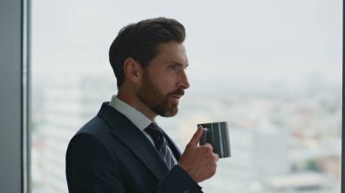 Cazibeli sakallı iş adamı kahve molasında ilham alıyor. Şehir manzarasında ofis penceresine bakıyor. Kendine güvenen yönetici portresi yeni fikir çözümleme sorunları yaratıyor..