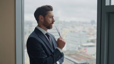 Havacılık sektöründe yatırım yapmak için kağıt uçak yapan düşünceli bir girişimci. Ofisin panoramik penceresinde duran uçak origamisine bakan kendine güvenen bir iş adamı yöneticisi..