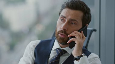 Kendine güvenen CEO müdürü iş ortaklarının müşterileriyle telefonda konuşuyor. Ciddi bir yönetmenin akıllı telefondan iş görüşmesi portresi. Patron iletişim için cep telefonu kullanıyor.