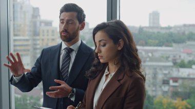 Kendine güvenen sakallı girişimci, ofis koridorunda duran kadın asistanlara iş sorumluluklarını anlatıyor. Ciddi bir CEO iş adamının sekreter iş süreçlerini göstermesi. Not alan kız