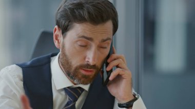 Akıllı yönetmen telefon oturarak işi tartışıyor. Orta yaşlı sakallı yönetici portresi. Uzaktan pazarlıkla akıllı telefondan konuşuyor. Kendine güvenen patron konuşuyor.