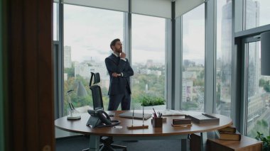 Üst düzey yöneticiler toplantı için modern ofiste panoramik pencerelerle dolaşıyorlar. Kendine güvenen sakallı iş adamı kol saatini kontrol ediyor. Çalışan iş gününün bittiğini düşünüyor..