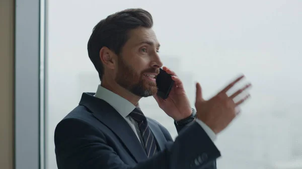 Mad man yelling on telephone standing company office close up. Angry bearded businessman talking emotionally on smartphone. Nervous man disappointed of business results screaming in phone dynamic.